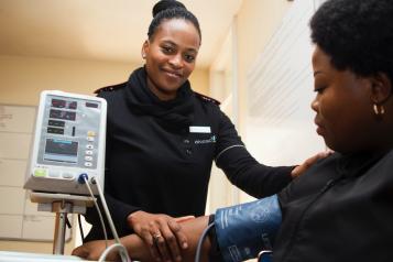 A black woman getting her blood pressure tested by a black female clinician