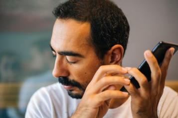 blind man uses phone to read something aloud