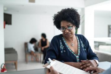 a black women reading a paper while standing at a counter