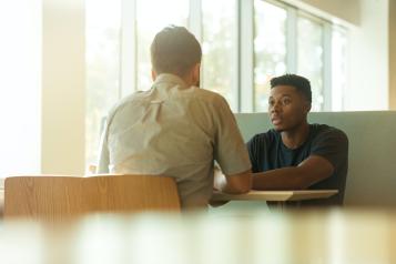 Young man talks to health professional in a bright room