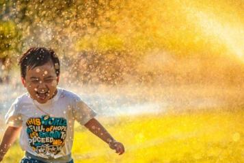 Photo by Mi Pham on Unsplash - Boy runs through sprinkler