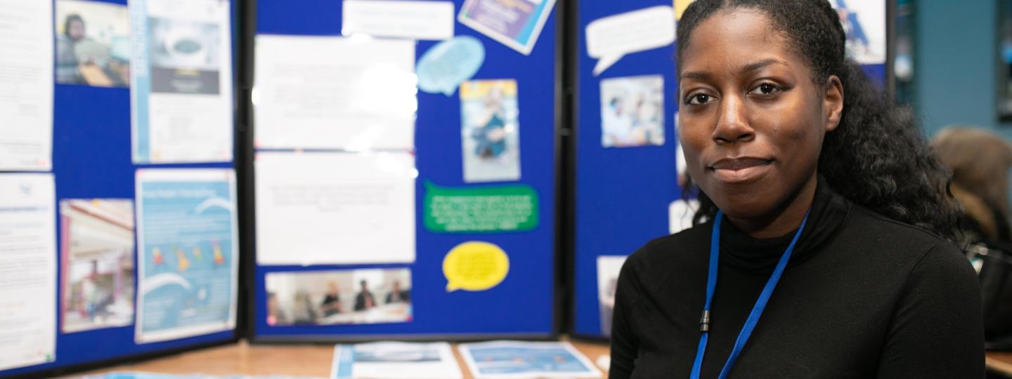 woman looks into camera with notice board behind her