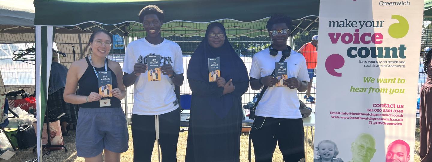 Healthwatch Greenwich young person's researchers standing in front of a stall holding leaflets about the HPV vaccine.