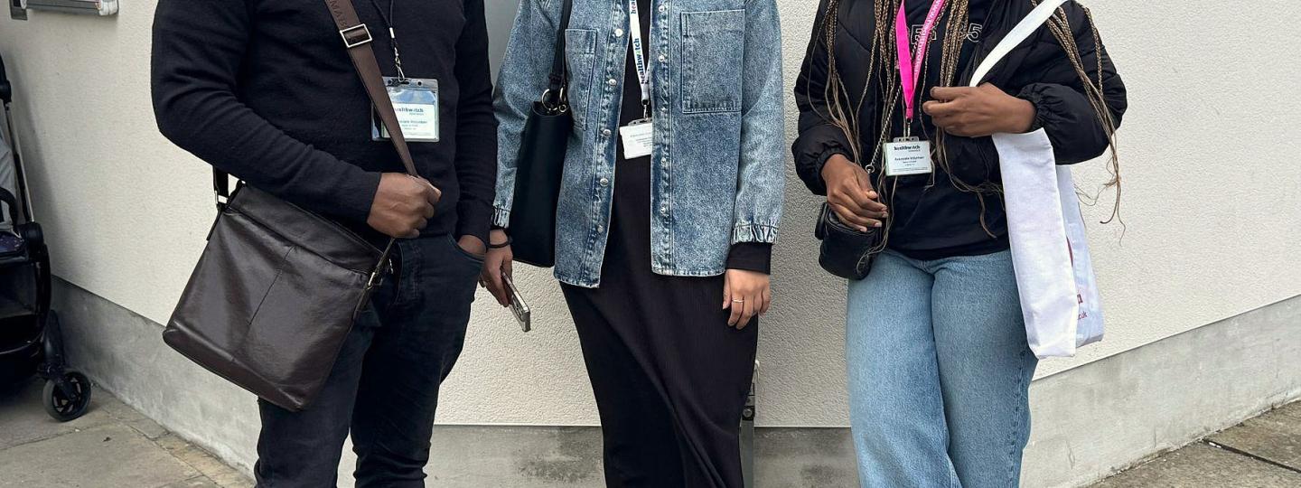 Three Healthwatch Greenwich volunteers standing in front of Woolwich Community Centre sign.