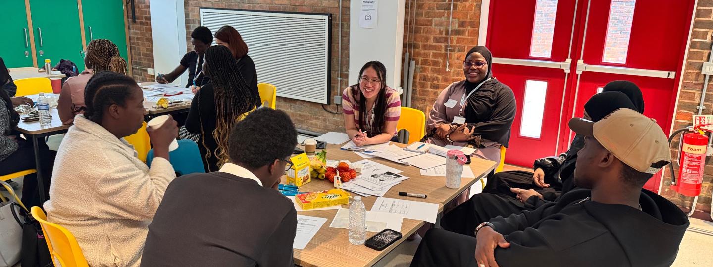 Young people seated around table speaking to Healthwatch Greenwich staff member.