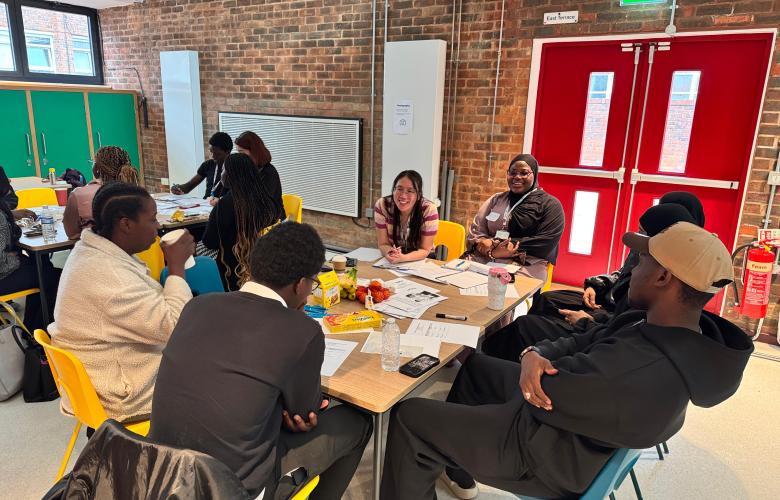 Young people seated around table speaking to Healthwatch Greenwich staff member.