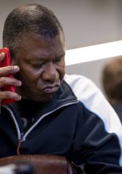 Man sitting at a table and holding a cell phone to his ear. 