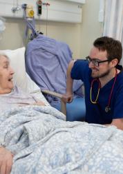Older resident in hospital bed speaking with doctor