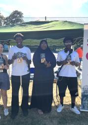 Healthwatch Greenwich young person's researchers standing in front of a stall holding leaflets about the HPV vaccine.