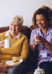 two old women in a care home laughing with their nurse